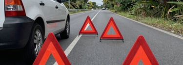 Tow truck assisting a stranded car on a roadside at dusk with city lights in the background.