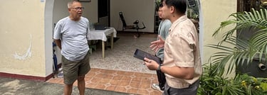 A real estate agent discusses a property with a client outside an arched house entrance.
