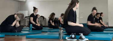 a group of people sitting on blue mats in a gym