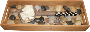 shea butter on wooden spoon on wooden tray with river rocks
