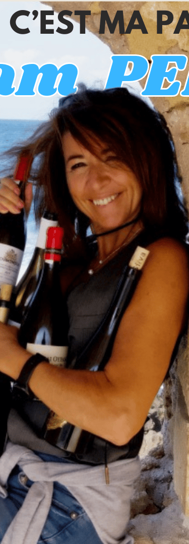 a woman sitting on a stone wall with a greek bottle of wine