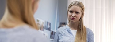 Jeune femme qui se regarde dans le miroir et doute d'elle-même