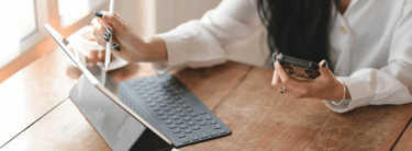 a woman sitting at a table with a mobile phone and a tablet reviewing company information