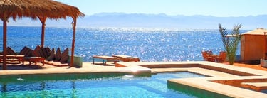 ein Pool mit einem Strohschirm und Stühlen