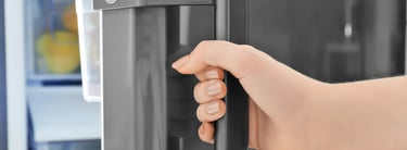 a person's hand holding a door handle on a refrigerator