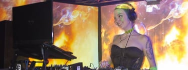 A smiling woman DJing in front of huge visual screens