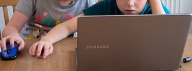 Two primary-age kids being creative with a laptop