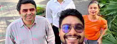 A diverse group of four smiling office colleagues taking an outdoor selfie at their workplace courtyard.