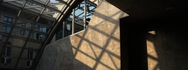 Low-key dramatic architectural close-up of a concrete and glass vault in Geneva, sharp geometric angles, dark shadows and gold light reflections, portrait aspect