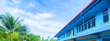 Blue grade school building with red roof and palm trees at Shelomith Learning Center, Inc.