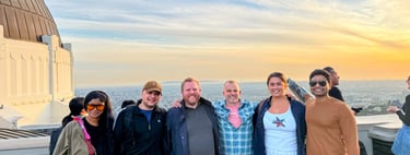 Diverse group of friends posing at Griffith Observatory during a vibrant Los Angeles sunset.