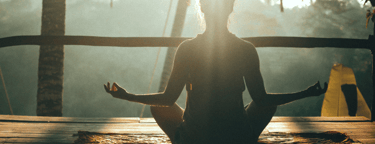 Person meditating in lotus position during sunrise at a tropical wellness retreat