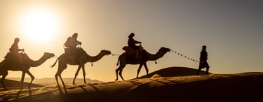a group of people riding camels in the desert