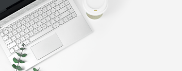 topdown view of workdesk with laptop, eucalyptus branch and coffee cup