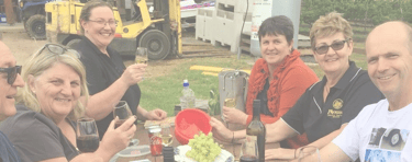 Happy people with wine and grapes at a picnic