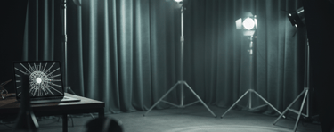 Professional studio setup with photography spotlights, curtains, and a laptop displaying graphic art.