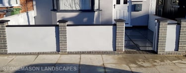 Blue perfurated brick wall with black coping and caps and grey rendering