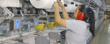 Operaria trabajando en línea de producción industrial textil durante grabación de video de procesos 