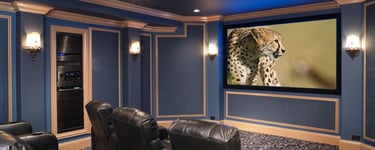 A high-end home cinema featuring a large projection screen, elegant black leather seating.
