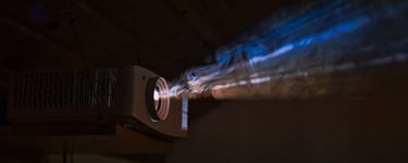 A close-up of a projector in action, casting a bright beam of light in a dimly lit space.