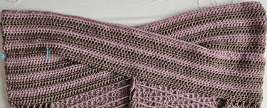 Handmade crochet crop top with a crisscross front design in pink and brown striped yarn.