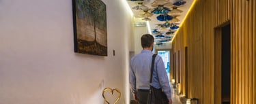 a man walking down a hallway with a table and chairs
