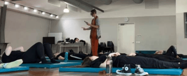 a man standing in a room with a woman on a yoga mat