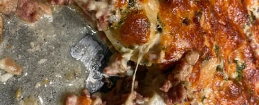 Homemade cheesy lasagna with golden brown crust, melted cheese, and savory meat sauce in a glass baking dish.