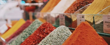 Colorful display of various spice powders in a Turkish spice market, featuring turmeric, chili powde