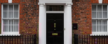 Exterior photography of a classic red-brick Georgian townhouse in Marylebone, London, with a traditional black front door and polished brass hardware.