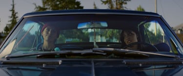 a man and woman in a car driving down a road