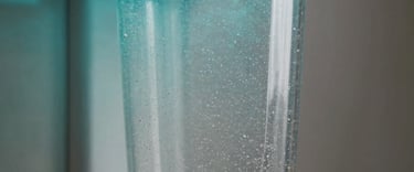 Close-up photography of a transparent laundry filter containing tiny particles, attached to a sleek metallic appliance, dramatic neon cyan lighting from the side.