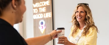 a woman is handing a cup of coffee to a customer