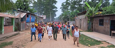 A community group guided by Roger Bardales walking down a dirt road in a indigenous shipibo village.