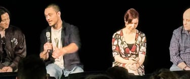 a man and woman sitting on a stage with microphones