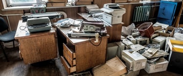 office space with great windows that is overrun with large amounts of clutter and unused supplies