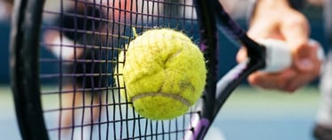 Dynamic close-up of a tennis ball compressing on racket strings, high contrast purple and yellow tones, action freeze frame, 35mm