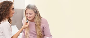 A woman holds an PurAroma essential oil bottle for another woman to smell.