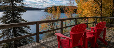 Muskoka chairs facing a lake view at sunset.