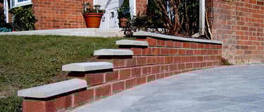 Premium grey block paver driveway and red brick wall with white coping