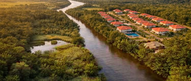 Vista aérea de condomínio residencial próximo a rio cercado por vegetação densa, i