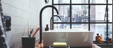 Modern bathroom vanity with a white vessel sink, matte black faucet, and a city view through a large window.