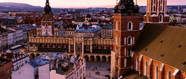 Krakow's Main Market Square at sunset featuring St. Mary's Basilica and Cloth Hall.