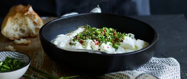 bol noir contenant de la faisselle avec de la ciboulette en morceau et baies rose dans un ambiance f