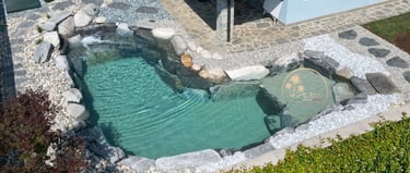 piscina con rocce e sabbia davanti al portico di casa