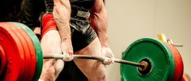 A muscular bodybuilder performing a heavy barbell deadlift during a powerlifting competition.