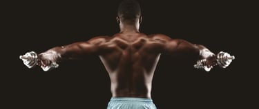 Back view of a muscular man performing lateral raises with dumbbells for shoulder strength training.