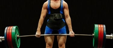 A strong male powerlifter performing a heavy deadlift with a weighted barbell and lifting belt.