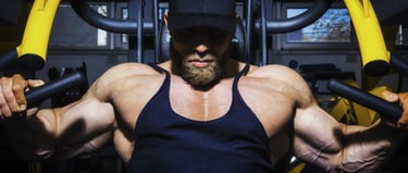 Muscular male bodybuilder performing a chest press on a yellow gym machine for strength training.
