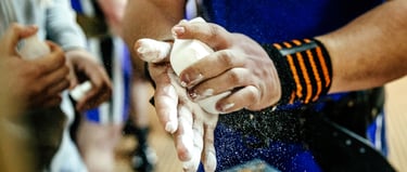 Weightlifter applying white lifting chalk to hands for better grip during a powerlifting workout.